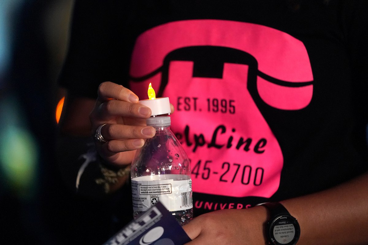 Close-up photo of someone wearing a T-shirt with a graphic of a pink telephone and the HelpLine phone number