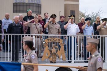 Michaelis in uniform saluting alongside others in crowd at football game