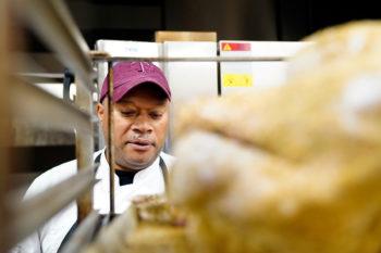 Chef Luke Rayford pictured looking at a turkey on a rack in the foreground