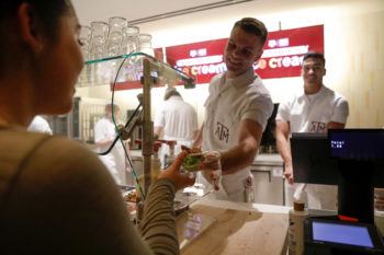 A yell leader standing behind a counter hands a student an ice cream cone