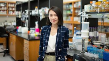 Chelsea Hu standing in her lab next to a work bench