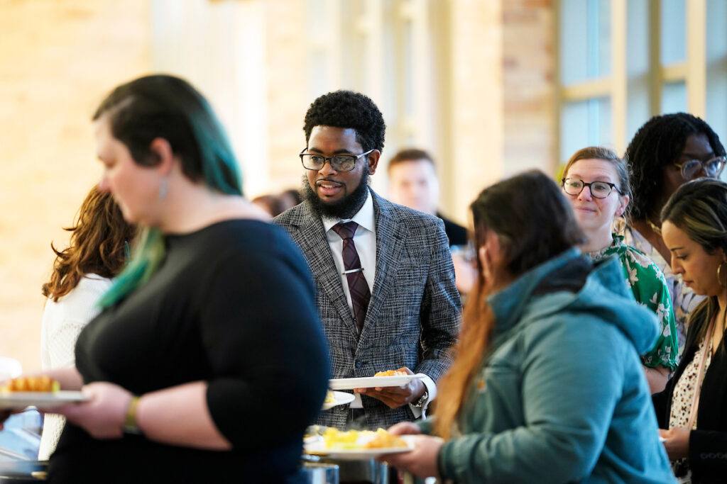 a photo of well-dressed people filling their plates with various breakfast foods