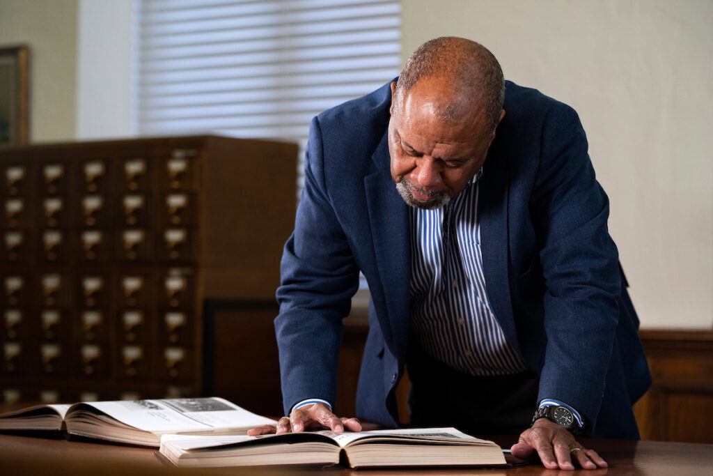 McClure standing at a table, bending over an open yearbook as he looks for his photo
