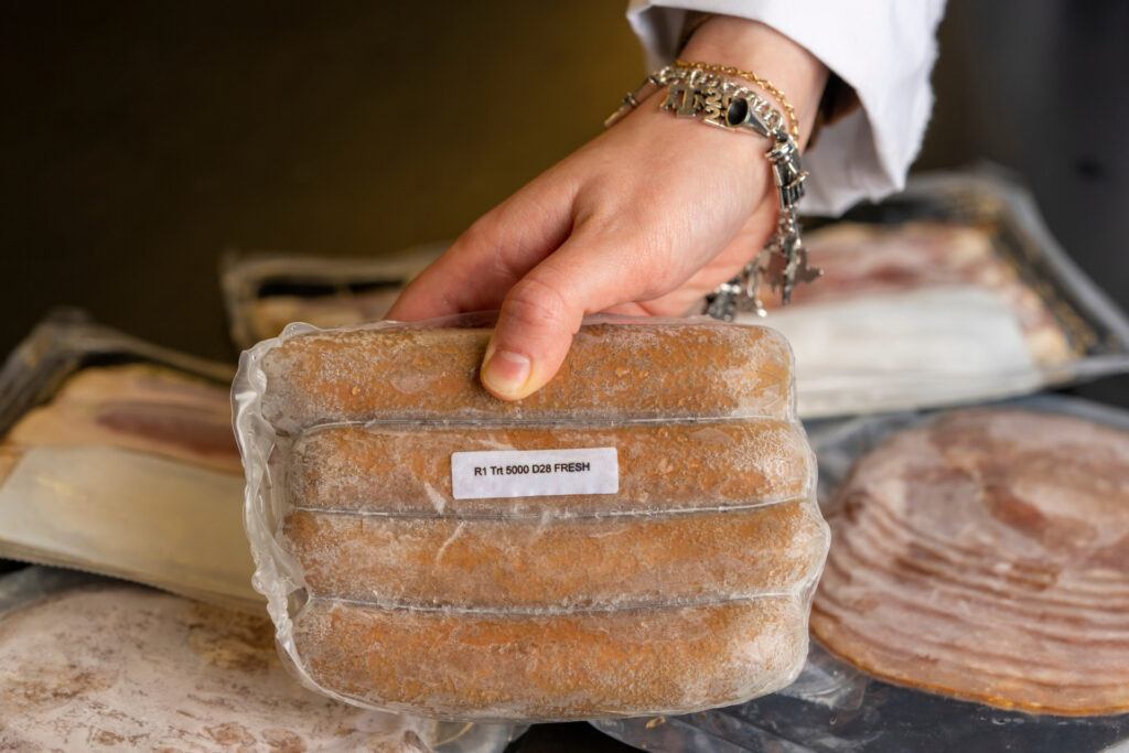 Close up photo of someone's hand displaying a package of frozen sausage links