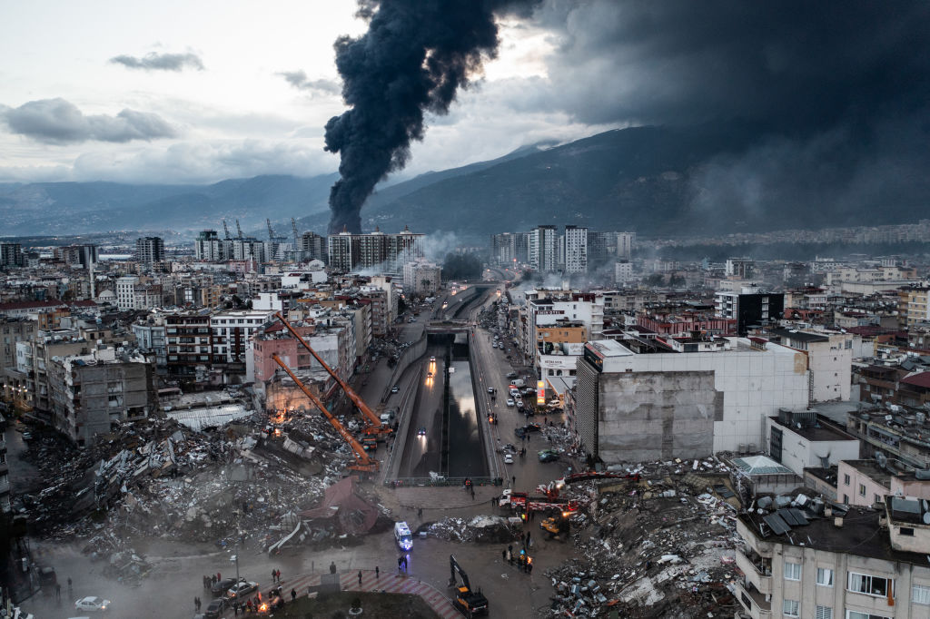 Collapsed buildings and rubble in Turkey with smoke billowing in the background
