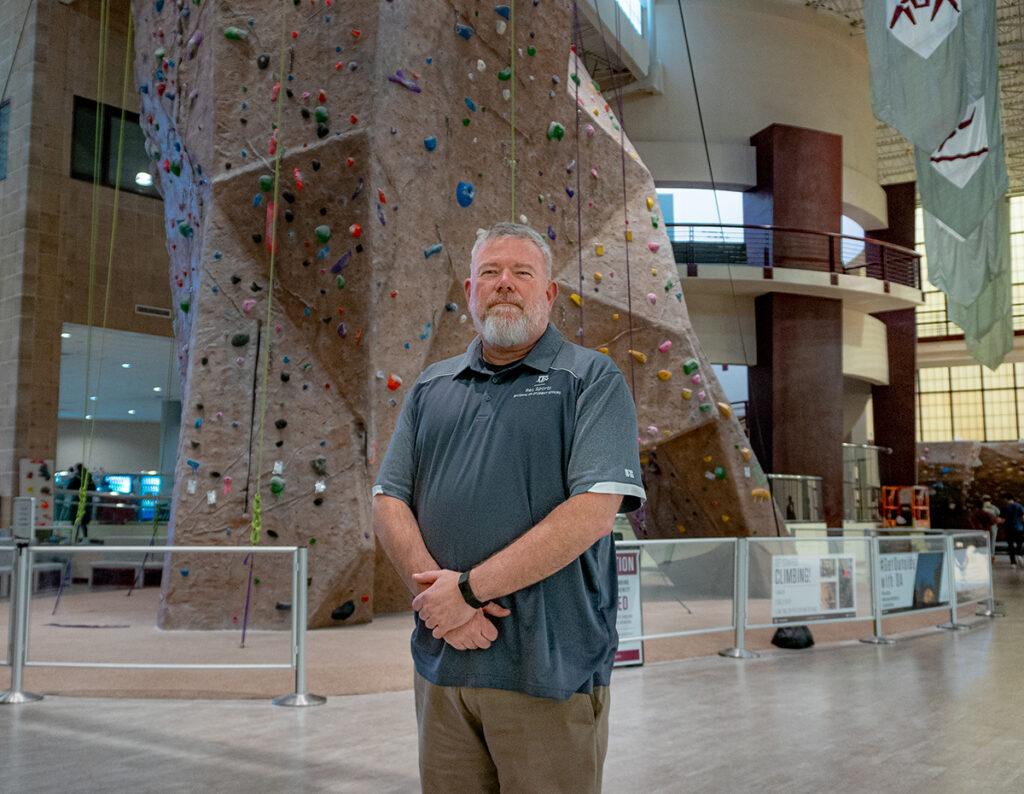 Jeff Huskey in front of the rock climbing wall at the Rec Center