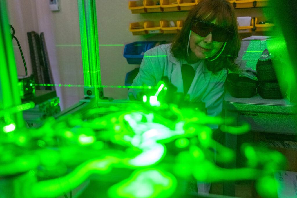 A green laser illuminates aerosolized particles with Dr. Maria King watching in the background