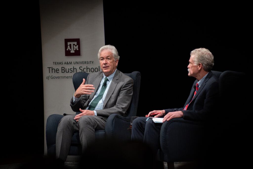 Bill Burns seated on stage next to professor Vogle