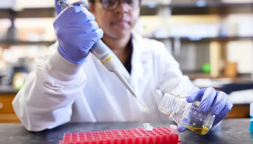 Photo of a person using a dropper in a lab setting.