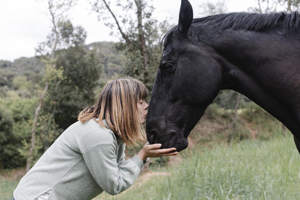 a woman kissing her horse on the nose