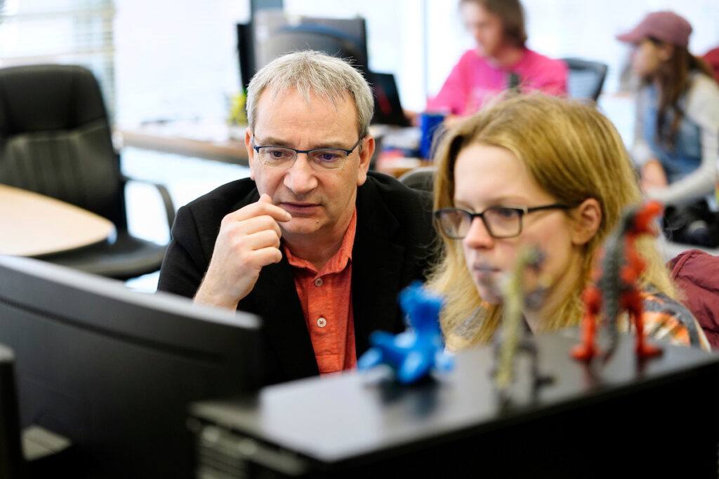 a photo of a professor and a student looking at a computer monitor