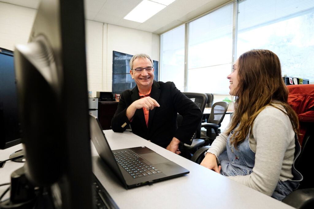a photo of smiles as he speaks with a college student sitting to his left