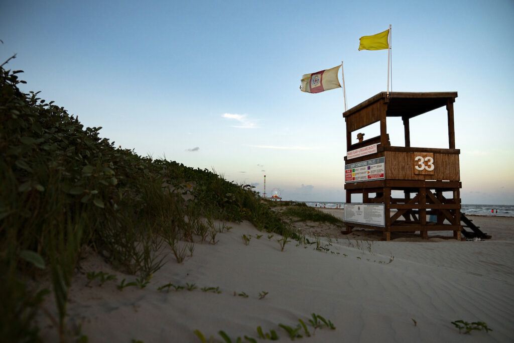 Sand dune with lifeguard tower on the beach at sunset