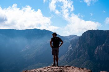a photo of a man standing on a cliff looking out into the distance