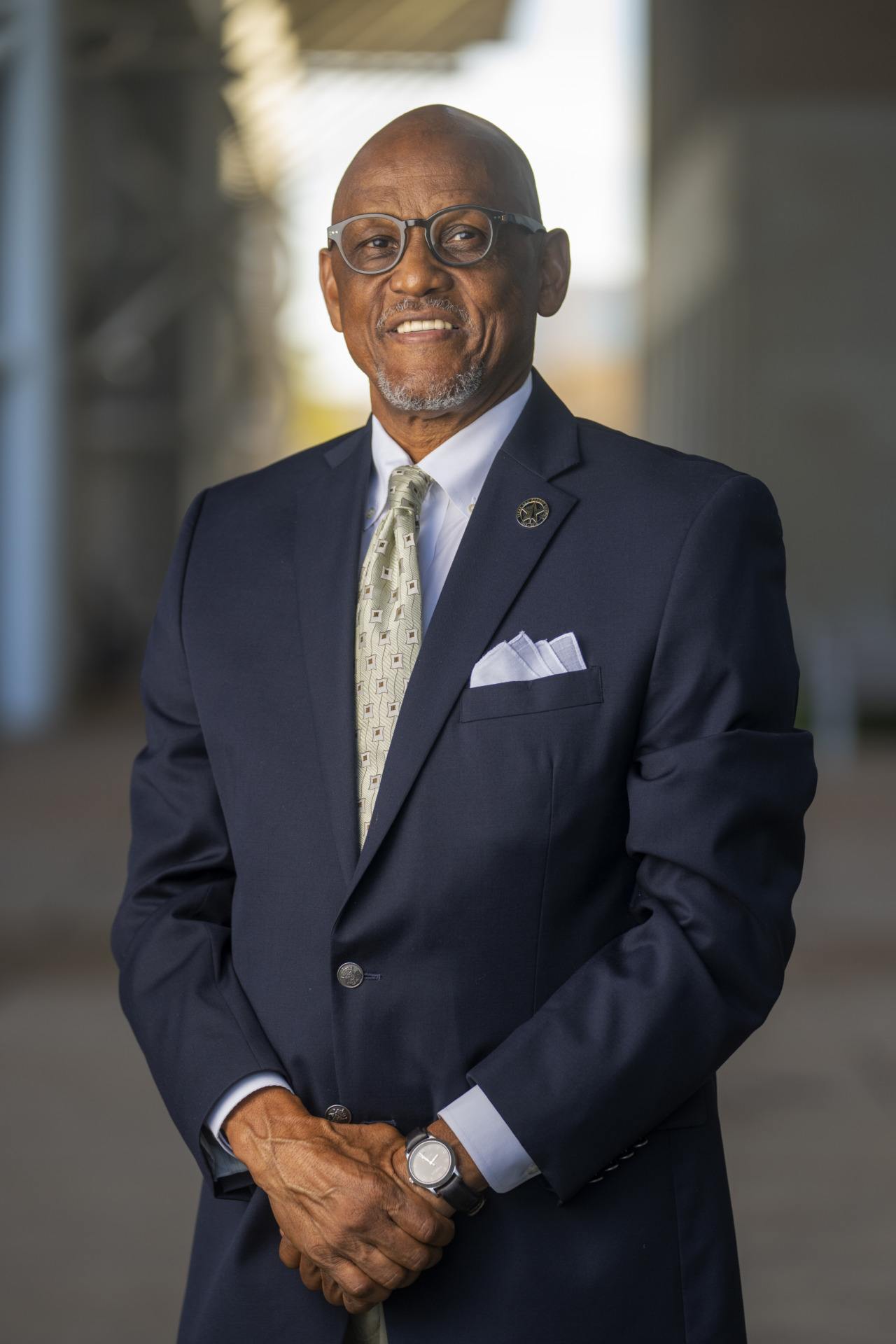 a portrait photo of a man with glasses in a dark blue suit