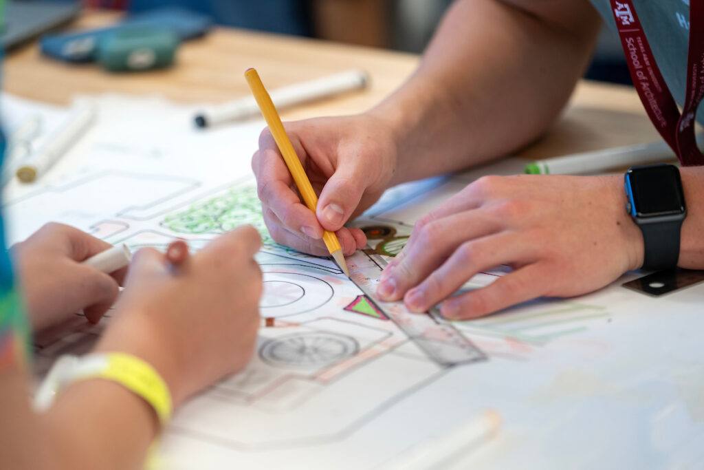 a student uses a ruler to draw a line on some architectural plans