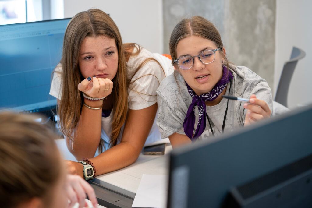 a photo of a woman in a purple bandana talking with students around a table