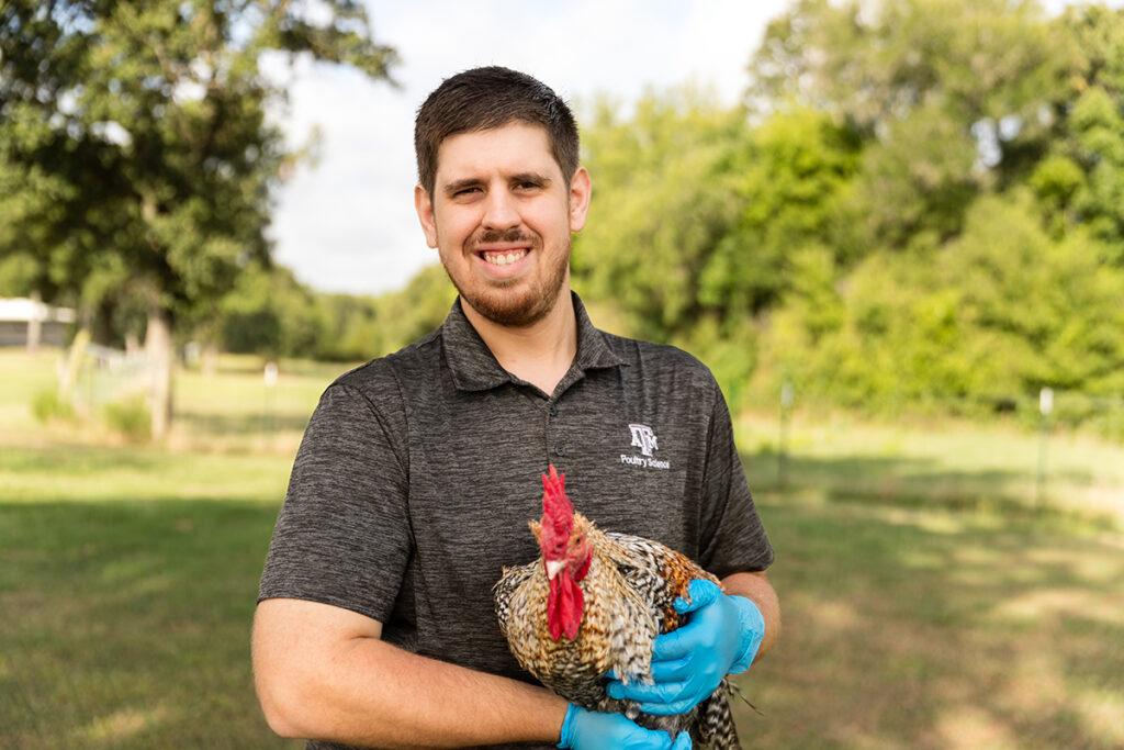 Texas A&M graduate student Nikolas Faust with a chicken