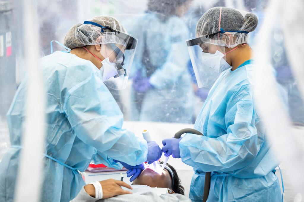a photo of two women in scrubs putting dental implements in a patient's mouth below