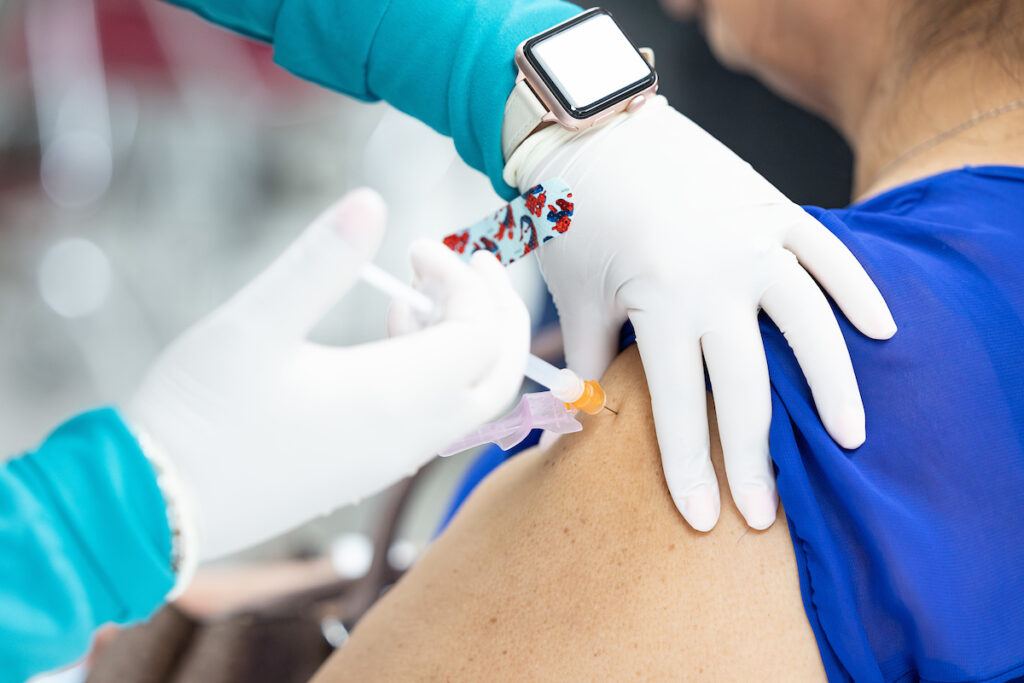 a photo of a woman being injected with a needle by a person in white gloves