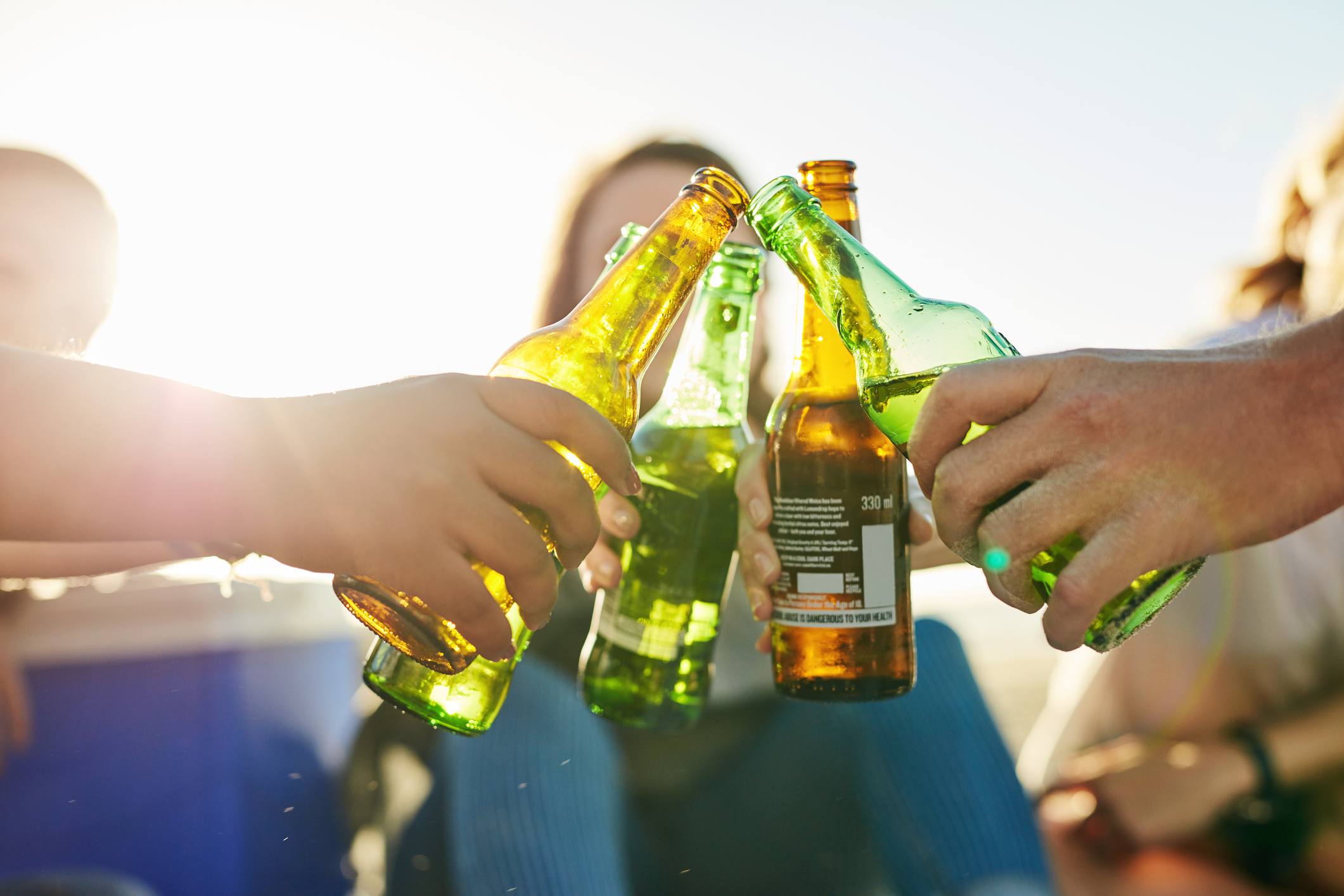 Shot of young people spending a summer’s day outdoors, clinking bottles of beer together