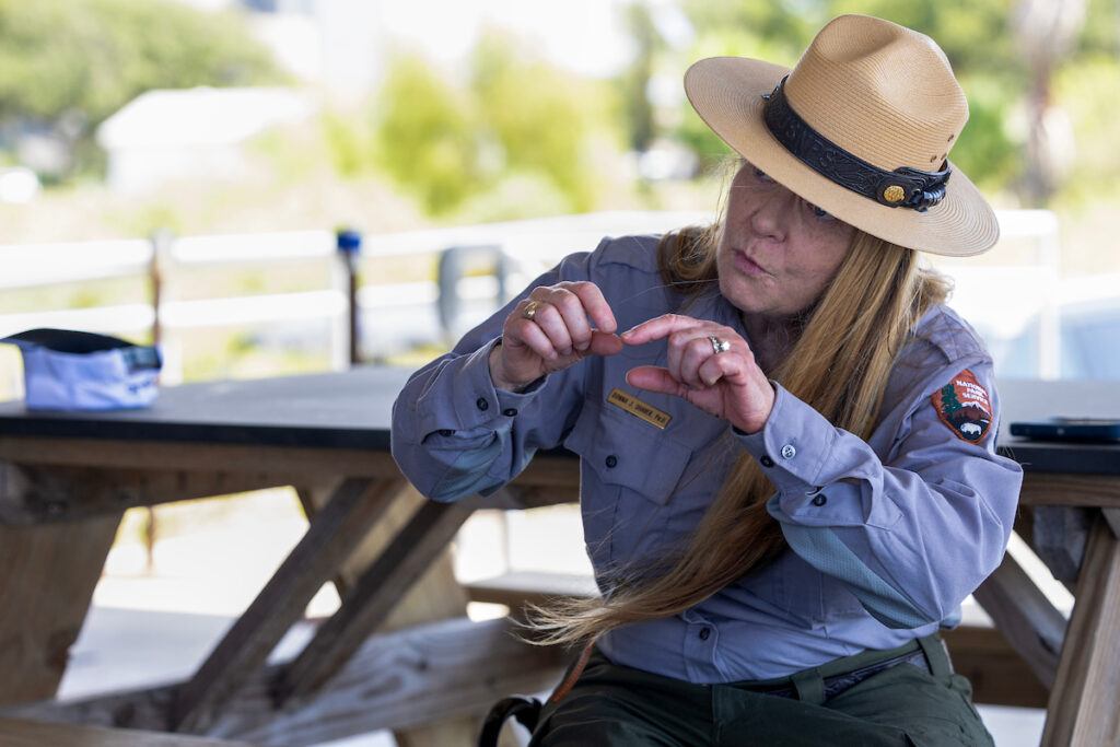 a photo of a woman in a national parks uniform sitting at a picnic table and talking