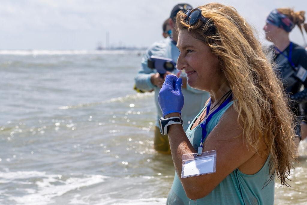 a photo of a woman looking off into the water with a bittersweet expression on her face