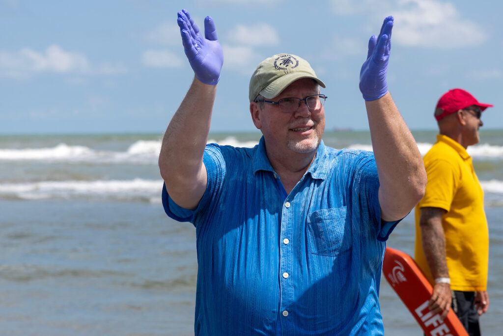 a photo of a man in a blue shirt and gloves clapping