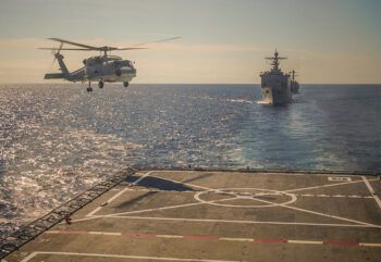 a helicopter landing on an aircraft carrier