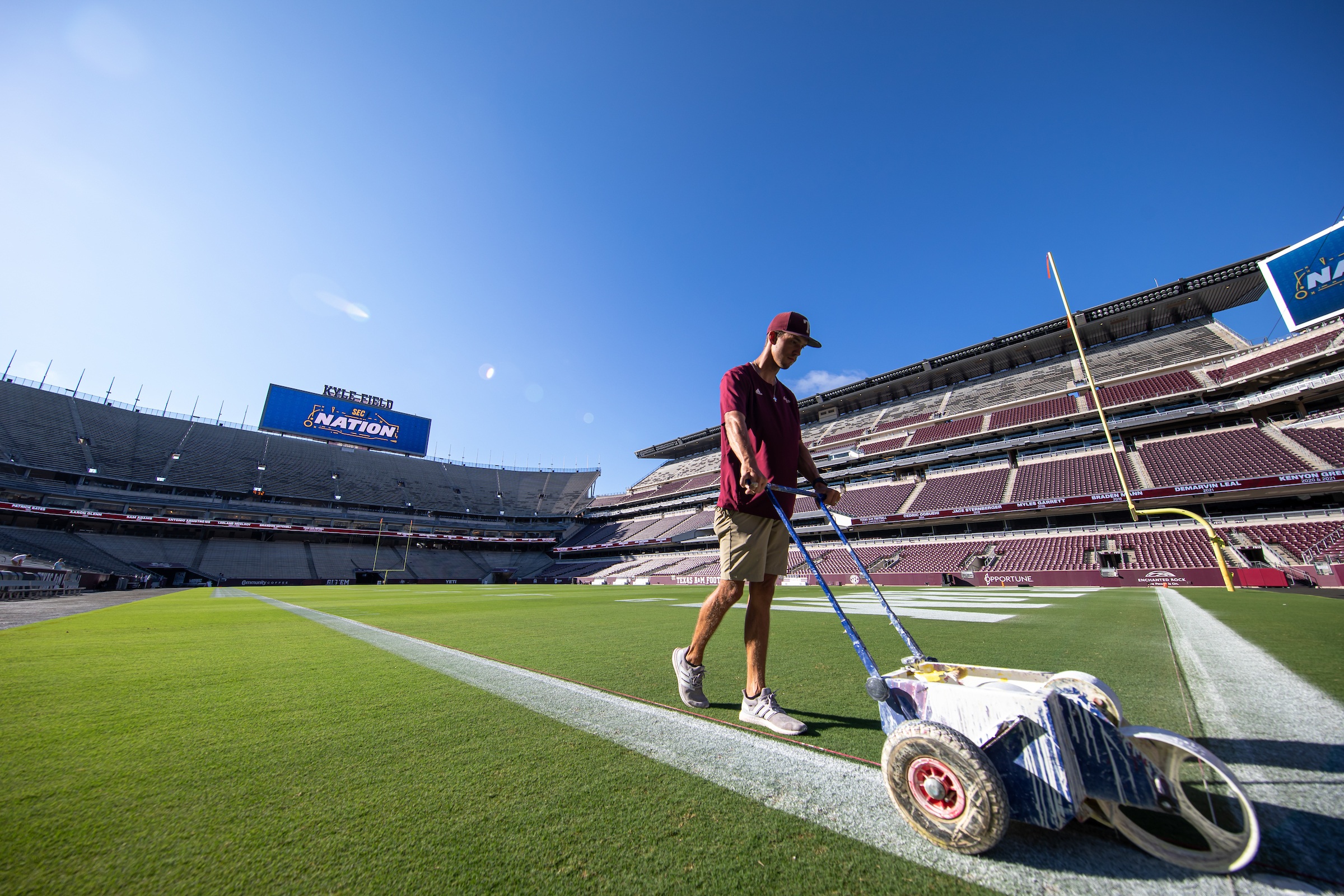 A man paints lines down Kyle Field on a sunny day