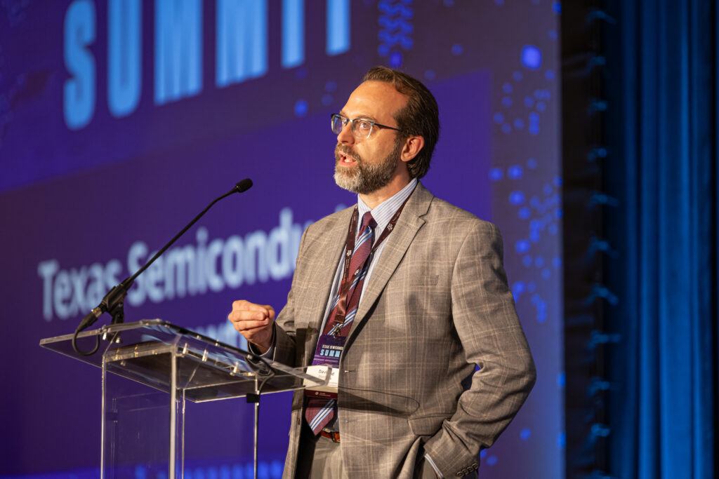 A photo of a man at a lectern during a conference.