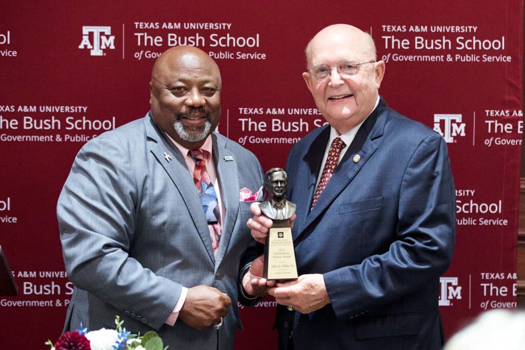 A photo of two men holding an award.