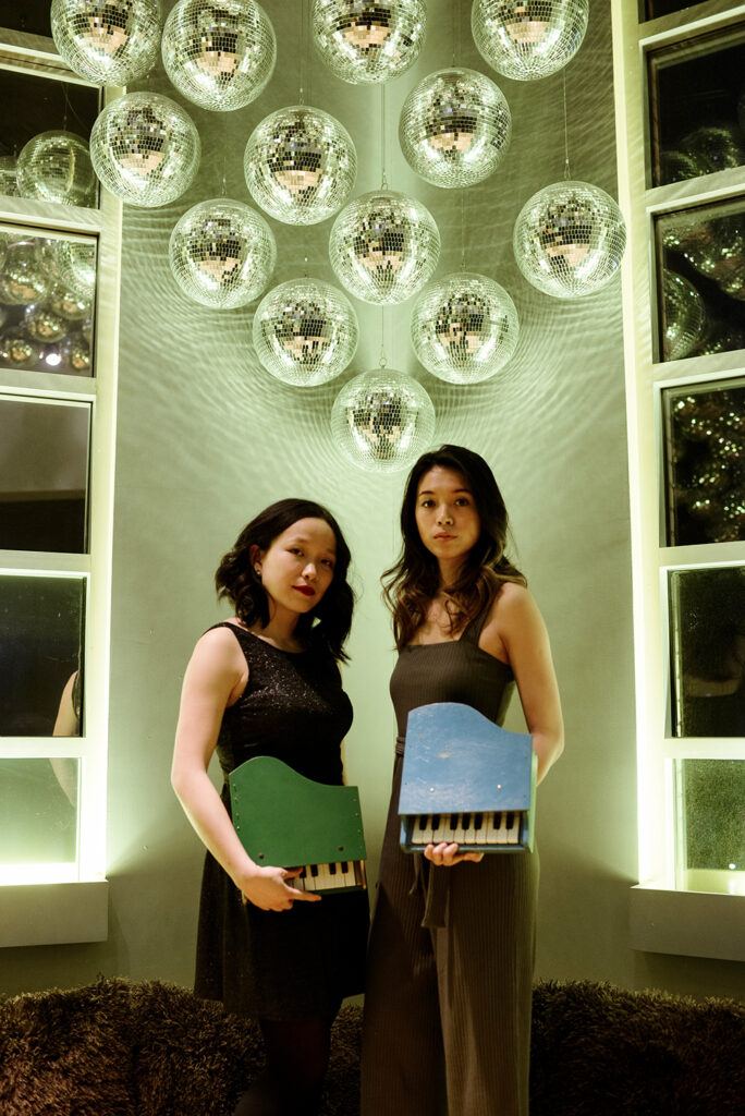 A photo of two women posing with toy pianos.