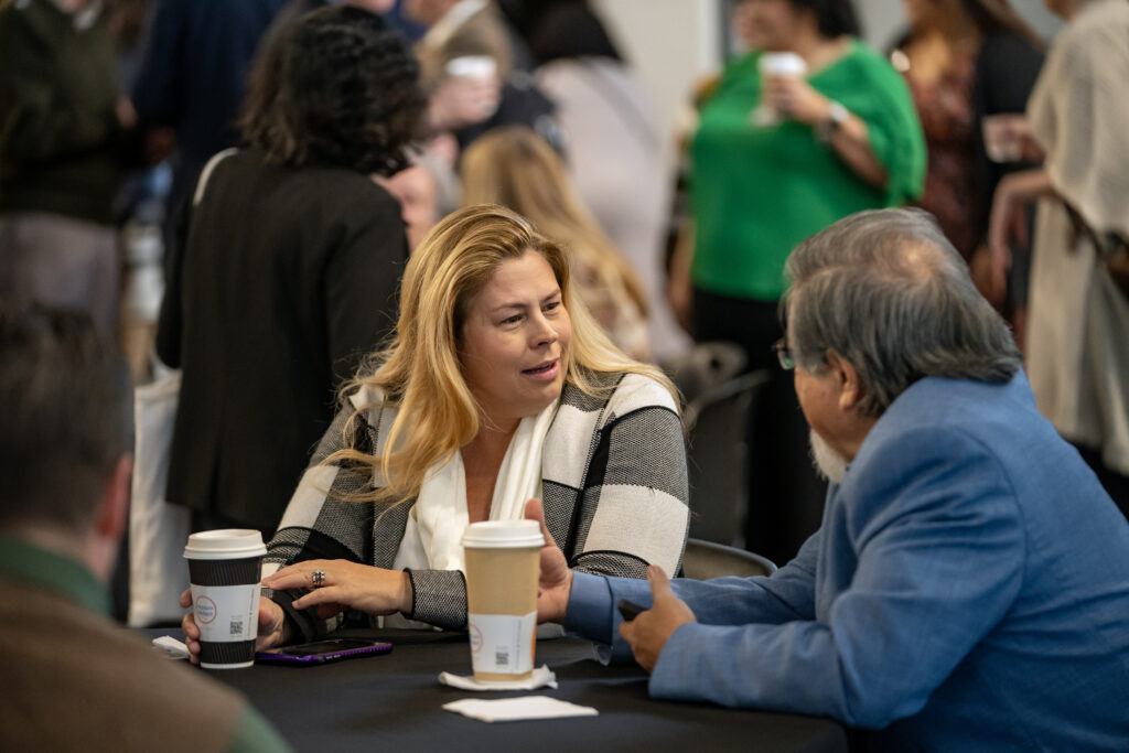a photo of two people talking while sitting at a table with coffee
