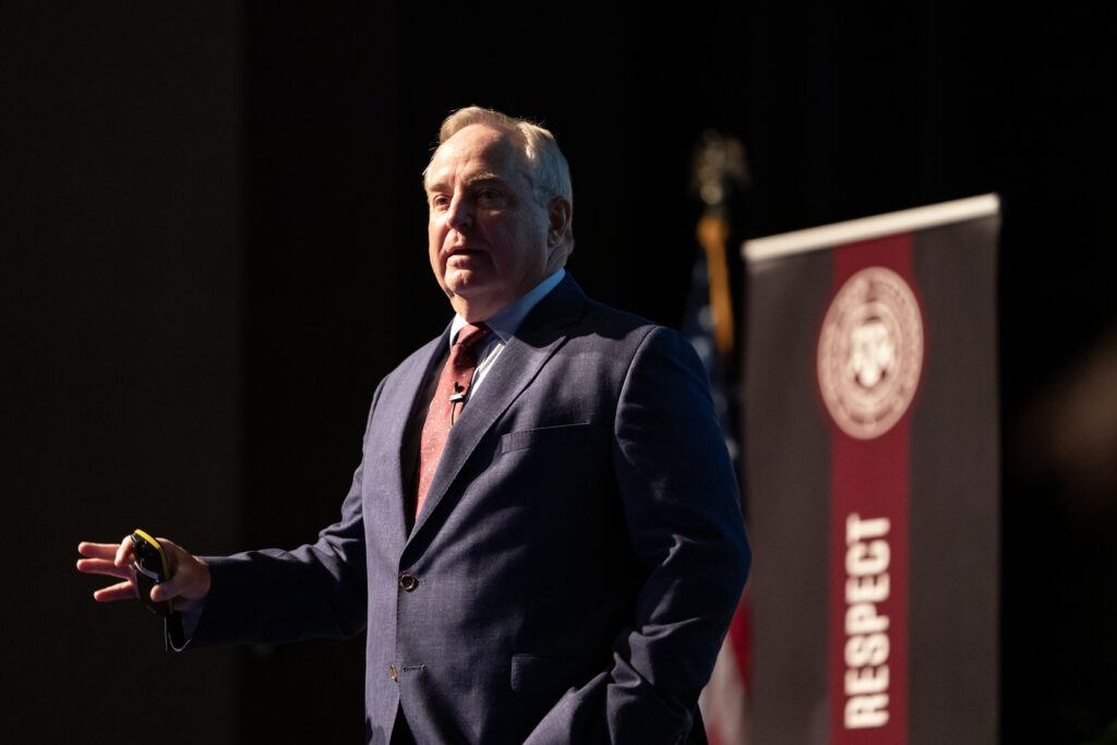 a photo of Mark A. Welsh III delivering the State of the University address on the Rudder Theatre stage.