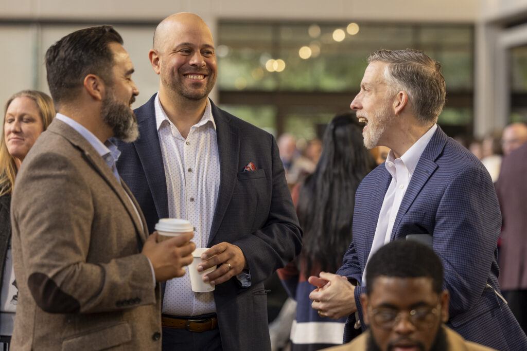 a photo of three people talking outside Rudder Theatre prior to the State of the University address.