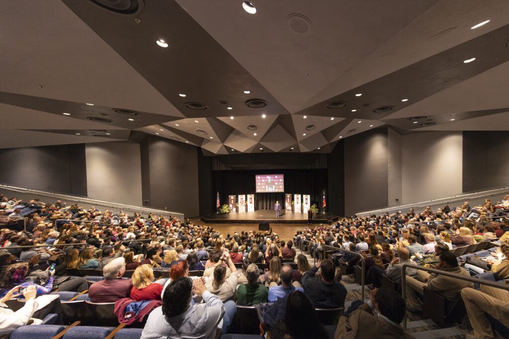 a photo of the crowd inside Rudder Theatre with Interim President Mark A. Welsh III on the stage.
