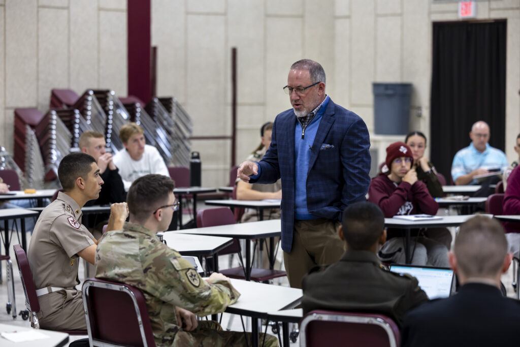 A photo of a man in a classroom talking to a student.