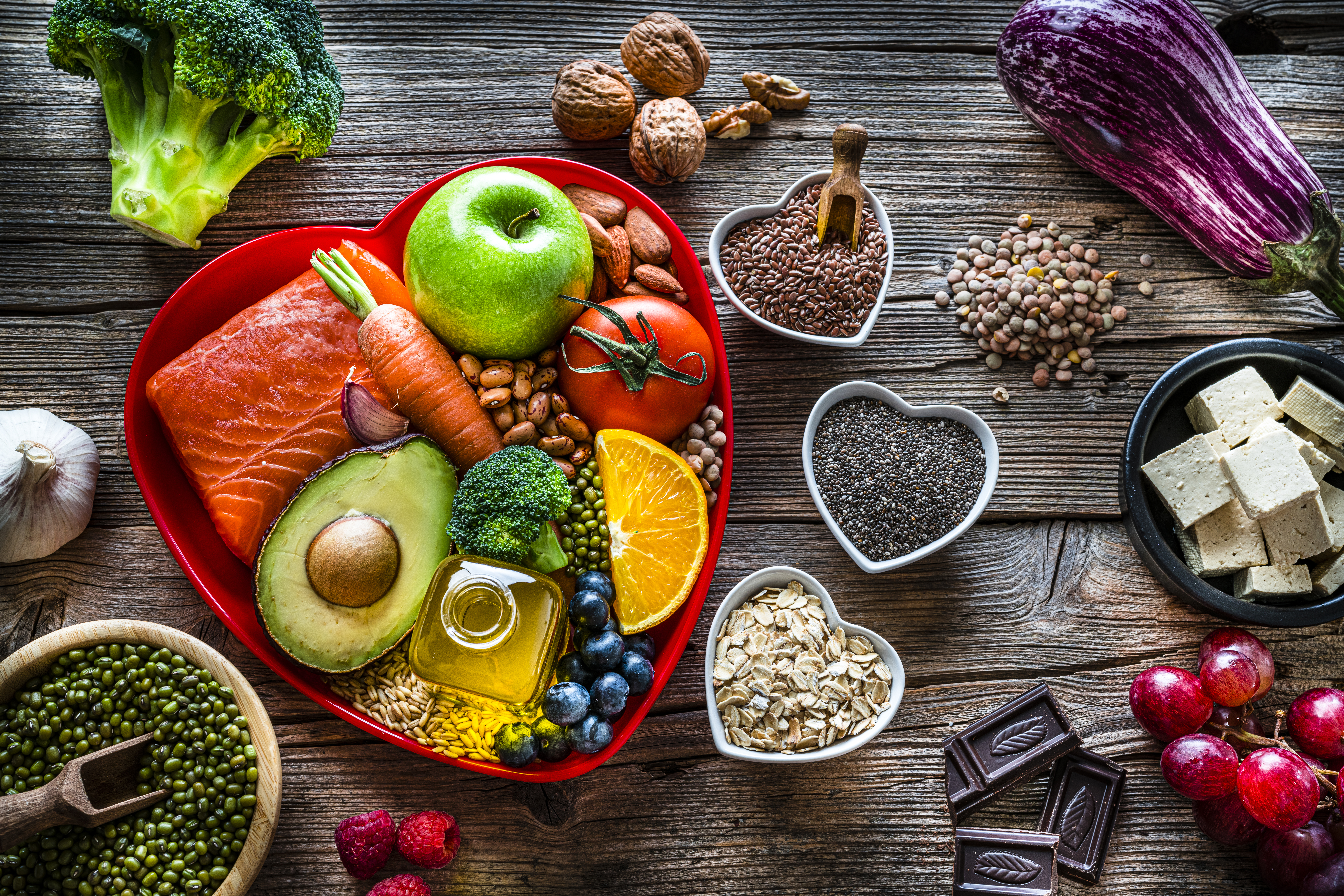 A photo of a group of fresh multicolored foods that contain flavonoids on wooden table.