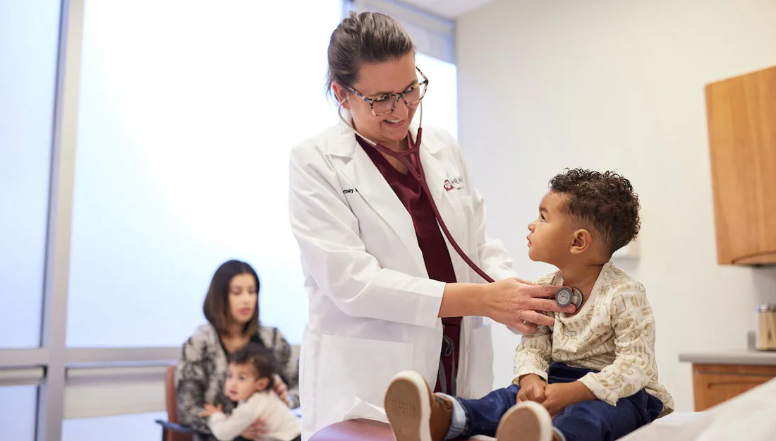 A photo of a doctor listening to a young boy's heartbeat with a stethoscope.