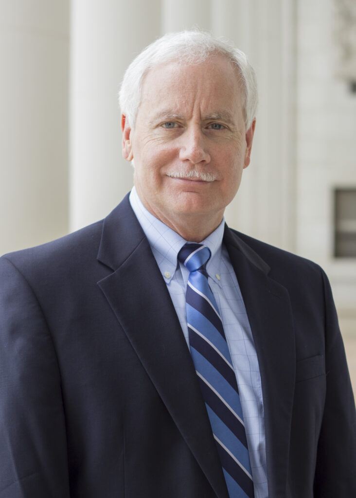 A photo of Dr. Mark Zoran in a blue suit with a blue striped tie.
