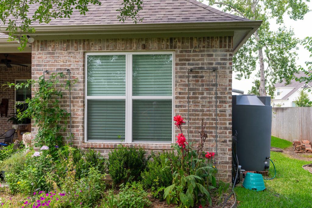 A water catchment system on the side of a brick home. Resolutions to save rainwater can help during times of drought and low moisture.