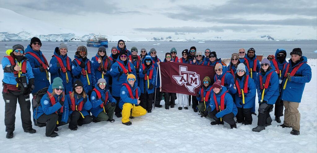 The study abroad group poses together in Antarctica with a Texas A&M flag