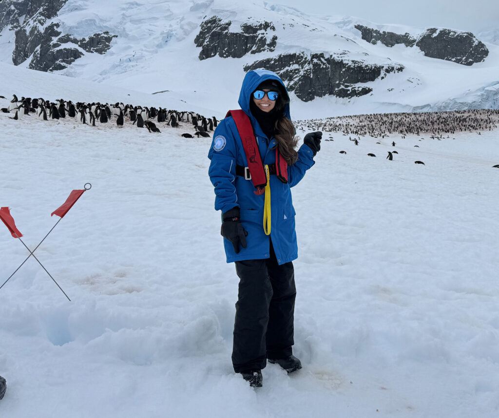 Mary Chandra stands before a group of Antarctic penguins