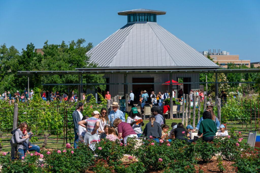 Dozens of people outside of a covered gazebo within The Gardens during an event