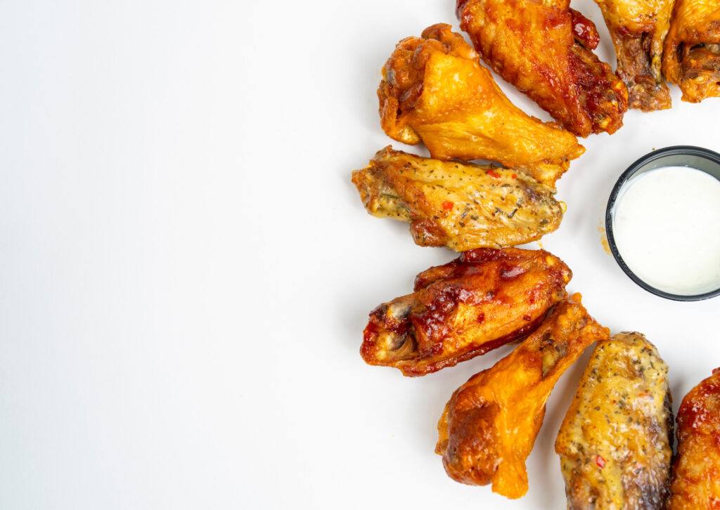 A variety of chicken wings with a small container of dressing in the middle.