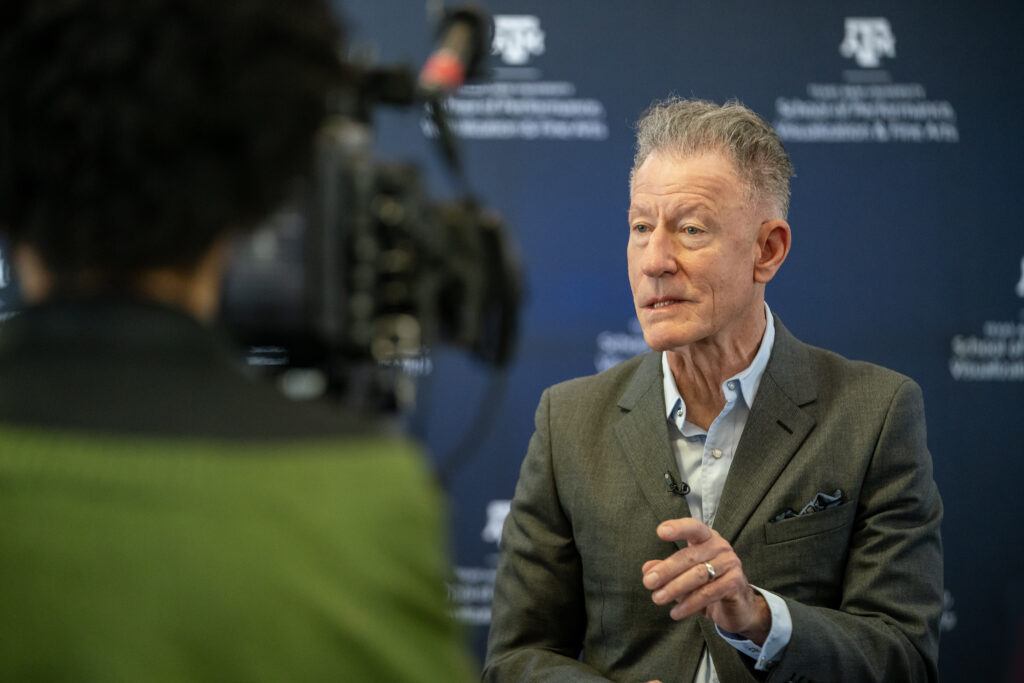 A photo of Lyle Lovett talking to the media.