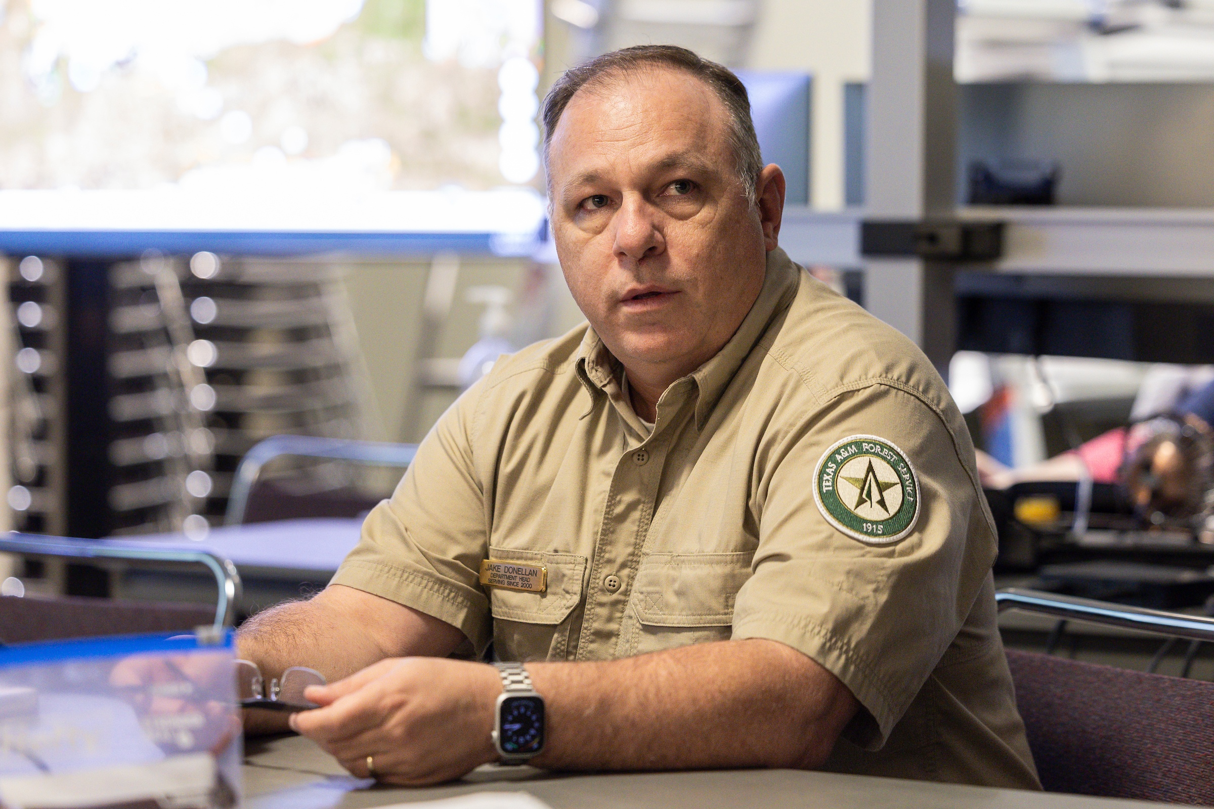 a photo of a man in a tan shirt with a Texas A&M Forest Service patch on the shoulder