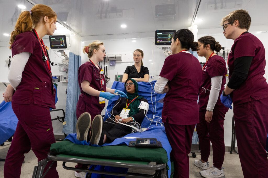 A photo of students caring for a victim on a hospital bed during a mass disaster training exercise.