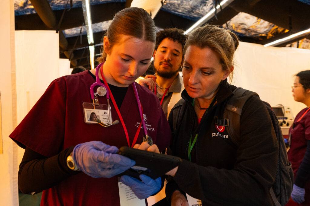 A photo of three people looking at a tablet during a disaster training simulation.